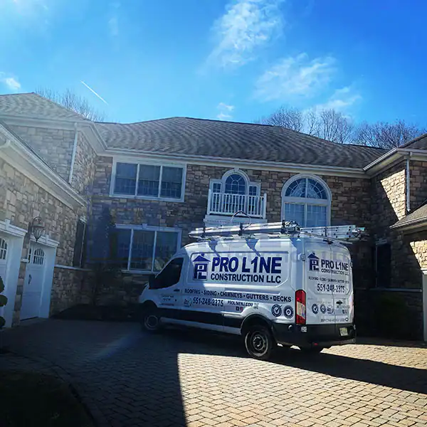 A Pro Line Construction LLC van, representing a trusted construction company in Morris & Essex County, NJ, is parked in the driveway of a large stone house with arched windows and a balcony under a sunny blue sky.
